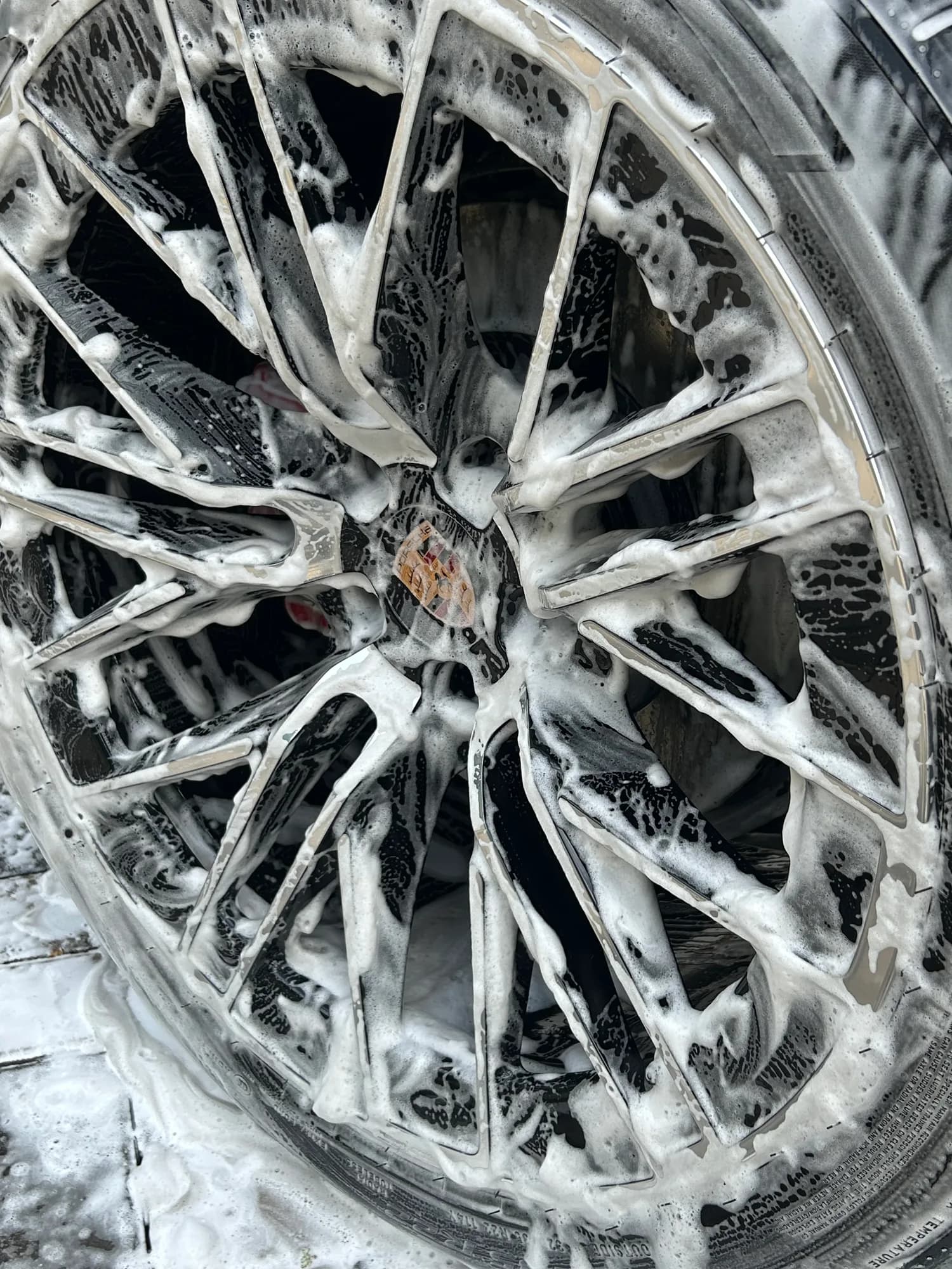 Porsche alloy wheel covered in foam during a safe wheel clean